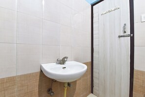 Un baño con un lavamanos blanco, paredes con azulejos y una puerta con marco negro.