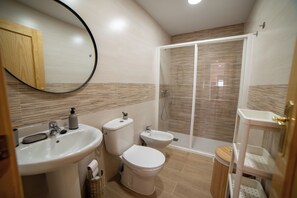Ein Badezimmer mit Waschbecken, zwei Toiletten, Dusche und Spiegel.