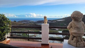 Ein Balkon mit Blick auf eine Küstenlandschaft, einer Statue und einem Geländer.