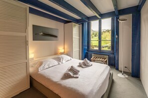 Ein Schlafzimmer mit einem Bett, zwei Nachttischlampen, einem Fenster mit Aussicht und einem Nachttisch.