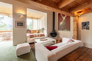 Ein gemütliches Wohnzimmer mit Kamin, einer Couch, einem Couchtisch und einem Essbereich mit Tisch und Stühlen.