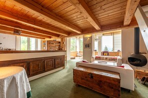 Ein rustikales Interieur mit Holzbalken, einer Küchenzeile, einer Couch und einem Kamin.