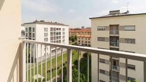 Ein Balkon mit Blick auf angrenzende Gebäude, einen klaren Himmel und einen Weg.