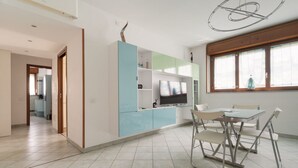 Eine moderne Küche mit Essbereich, einem Fernseher und einem Fenster mit Jalousien.