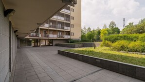 Ein mehrstöckiges Gebäude mit Balkonen, einem überdachten Gang und einer angelegten Gartenanlage.