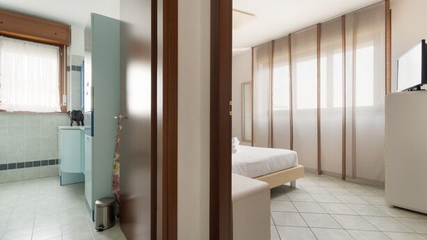 Ein modernes Hotelzimmer mit Bett, kleinem Schreibtisch, Toilette und Duschbereich.