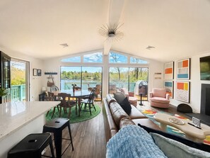 A spacious living room with a large window, a dining area, and a cozy seating area.