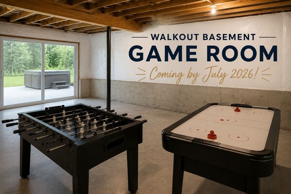 Une salle de jeux équipée de deux tables de baby-foot et d’une grande banderole annonçant l’ouverture prochaine de la salle de jeux Walkout Basement, prévue pour juillet 2026.