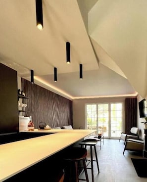 A modern kitchen with a long counter, pendant lighting, and a dining area with a sofa and chairs. - Casa iKa Port Grimaud - Fishing houseeur 4 Rooms with mooring (Grimaud)