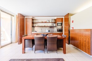 Een moderne keuken met een eethoek, inclusief een tafel en stoelen, en uitzicht buiten via een schuifdeur.