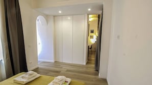 A hotel room with a bed, a sofa, a wardrobe, and a bathroom visible through an arched doorway. - Apartment in Pigneto (Rome)