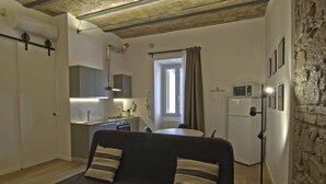 A compact living space with a kitchenette, a dining area, and a sofa with cushions. - Apartment in Pigneto (Rome)