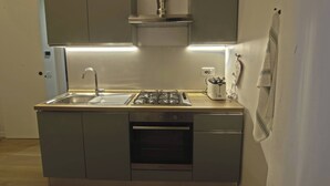A compact kitchen with a sink, stove, oven, and cabinets. - Apartment in Pigneto (Rome)