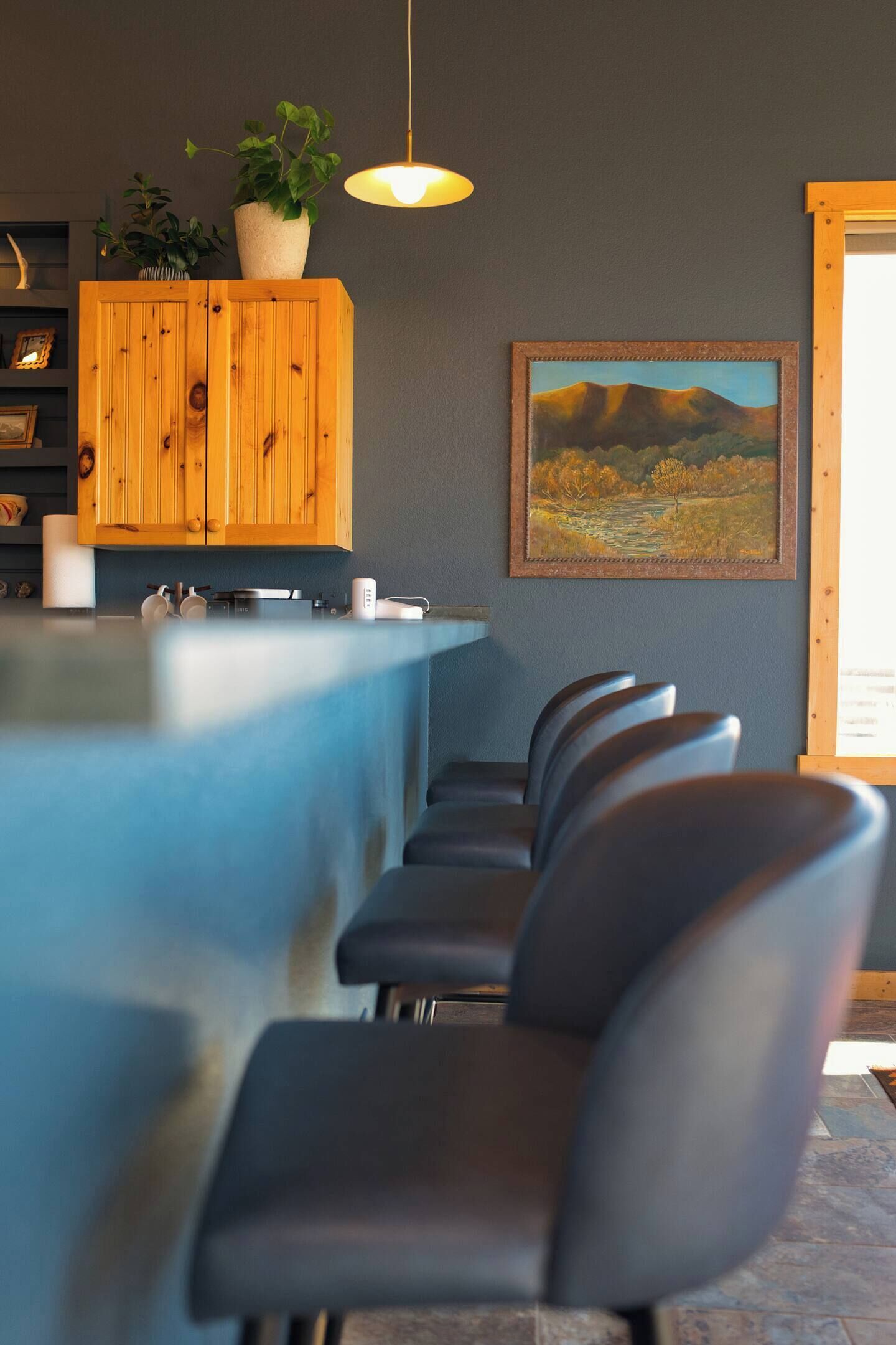 A modern kitchen with wooden cabinets, a bar area, and a seating section with chairs.