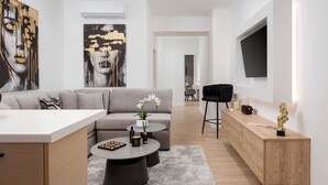 A modern living room with a sofa, coffee table, and artwork. - Aura Airport Suite (Spata)