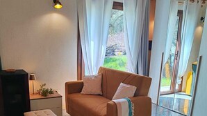 Una habitación acogedora con un sofá, una mesita con una lámpara y una cama con una toalla enrollada.