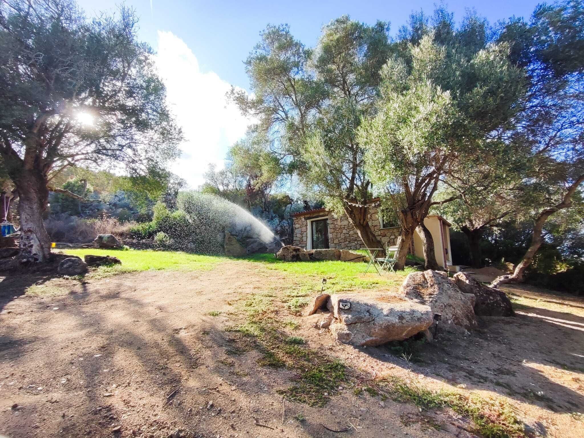 Un cadre extérieur rustique, avec un bâtiment en pierre, des arbres et un ciel dégagé.