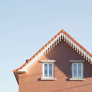 A house with a red roof, two windows, and a stone base.