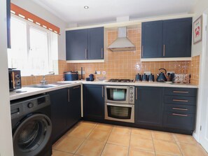 Cuina compacta amb rentadora, forn i fogó de gas.