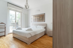 Una camera da letto con un letto grande, una finestra, un termosifone, un lampadario e un quadro appeso al muro.