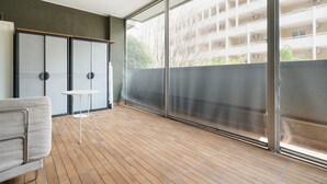 En balkong med utsikt över en byggnad, en stol och ett litet bord.