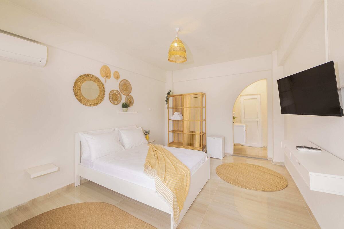 Une chambre à coucher comprenant un lit, une télévision, une table de chevet, une armoire et un miroir.