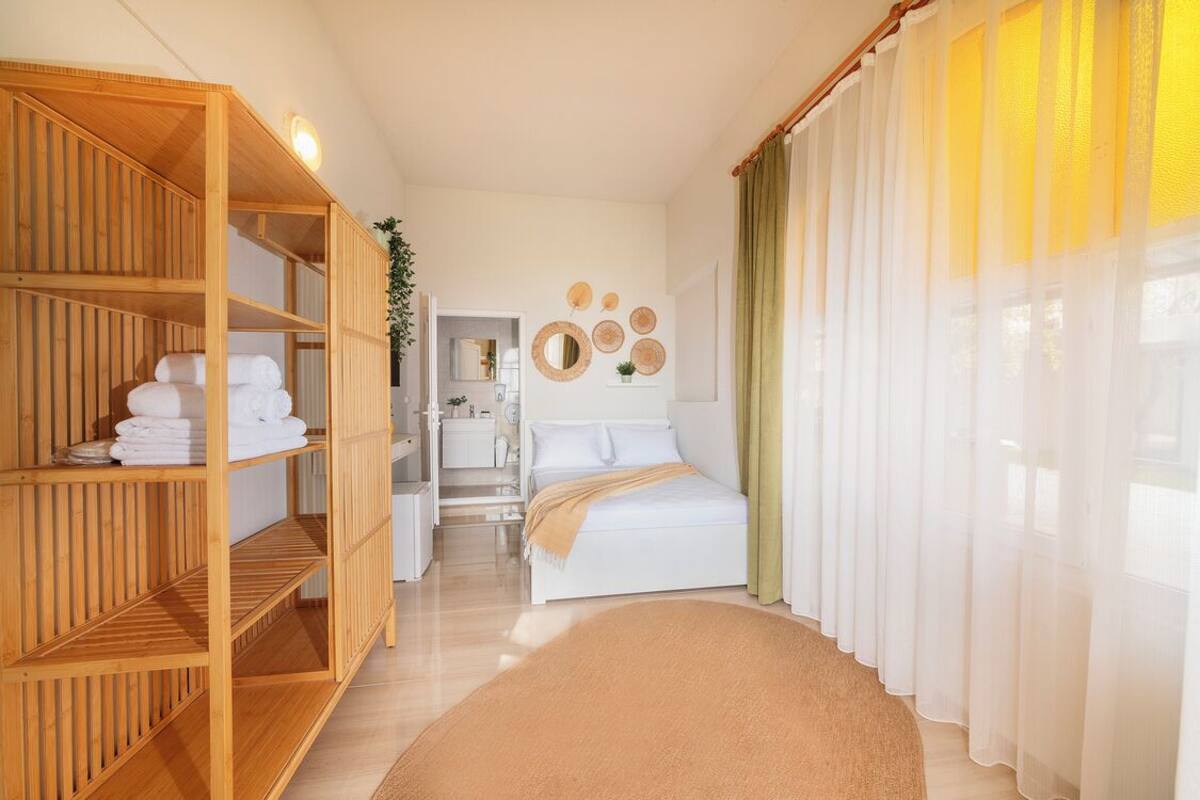 Une chambre d’hôtel avec un lit, une armoire en bois, une salle de bain et une vue sur l’extérieur.