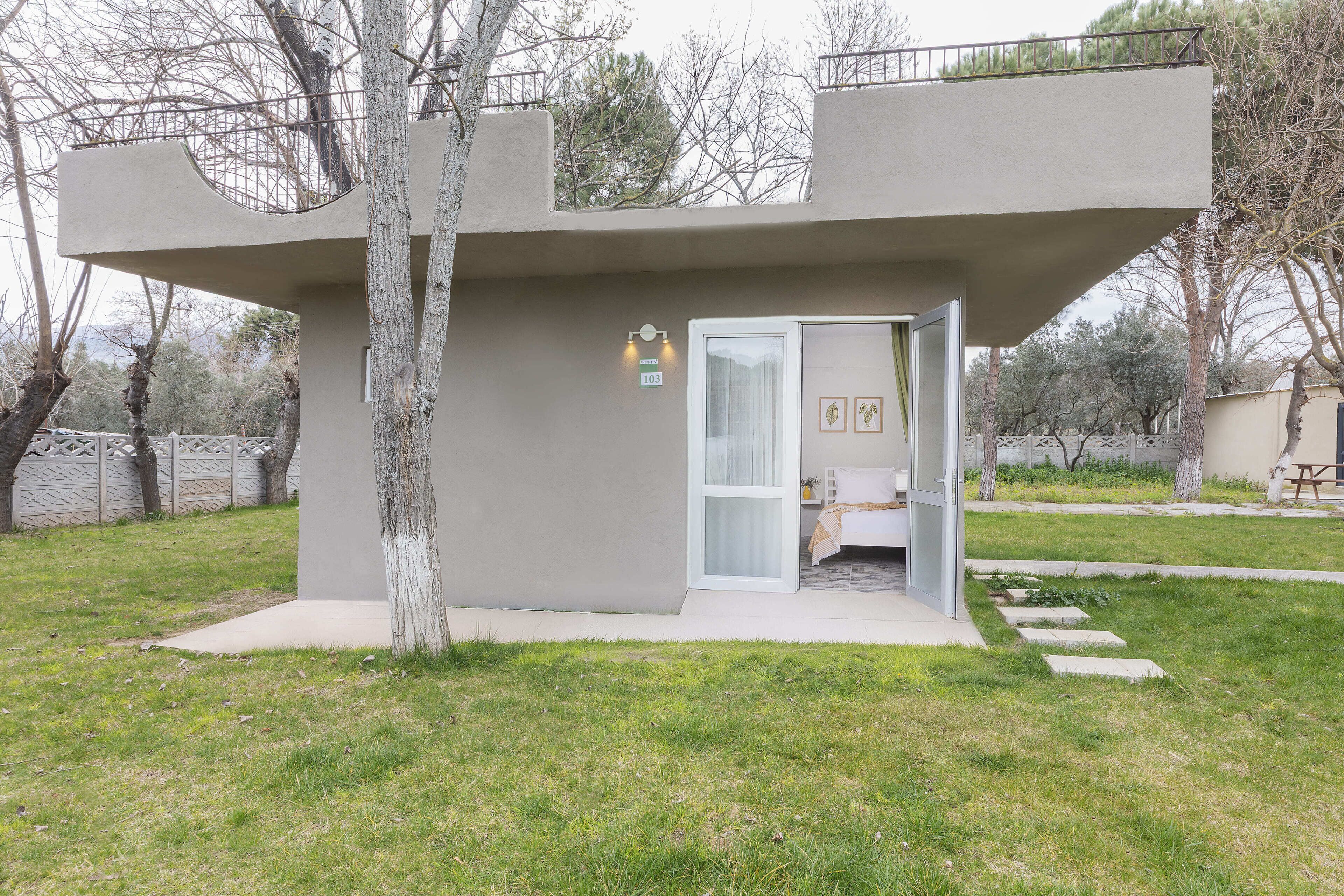 A modern building with a unique architectural design, a door, and a small outdoor area.