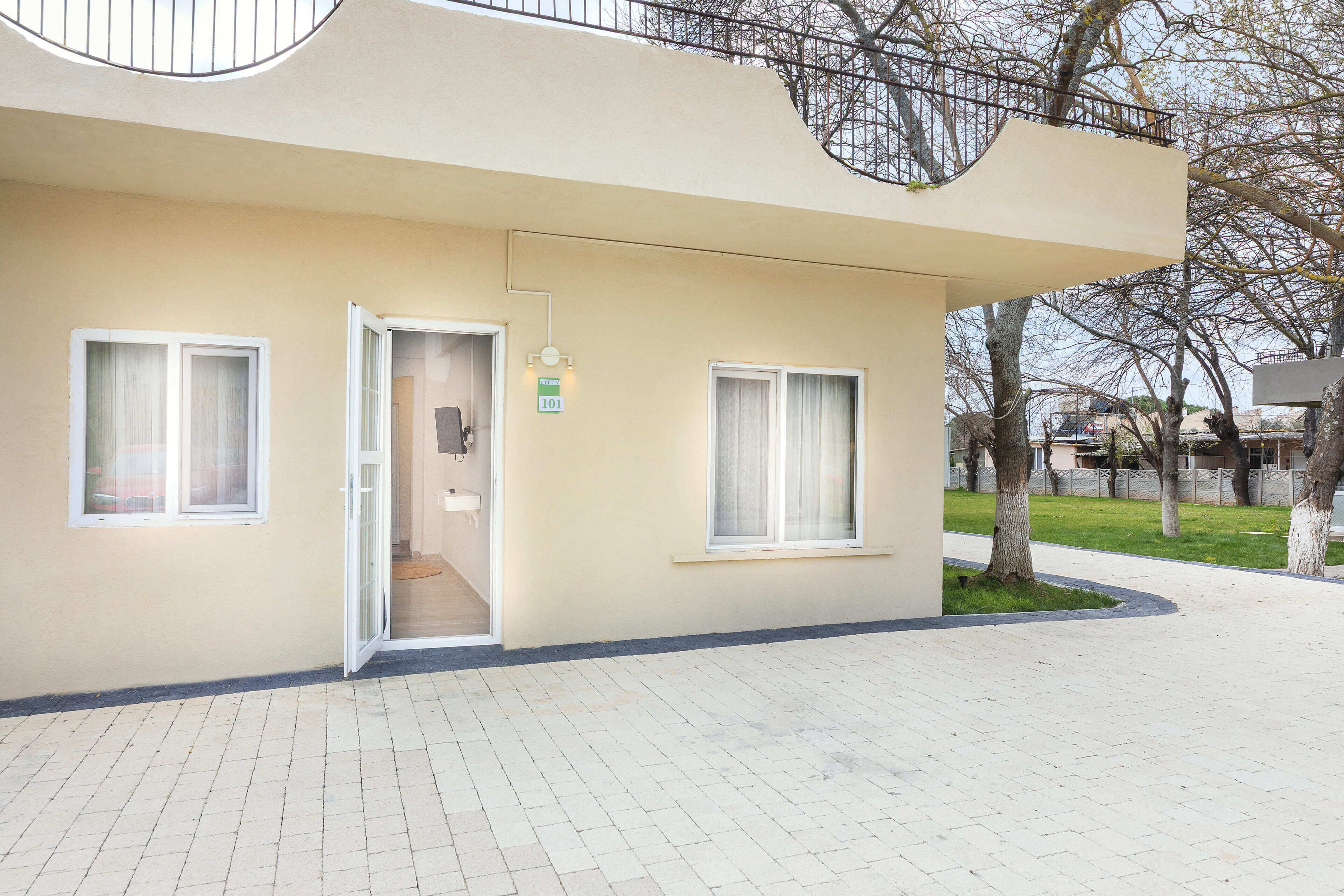 Un edificio moderno con fachada plana, dos ventanas, una puerta y un pequeño letrero que indica la habitación número 101.