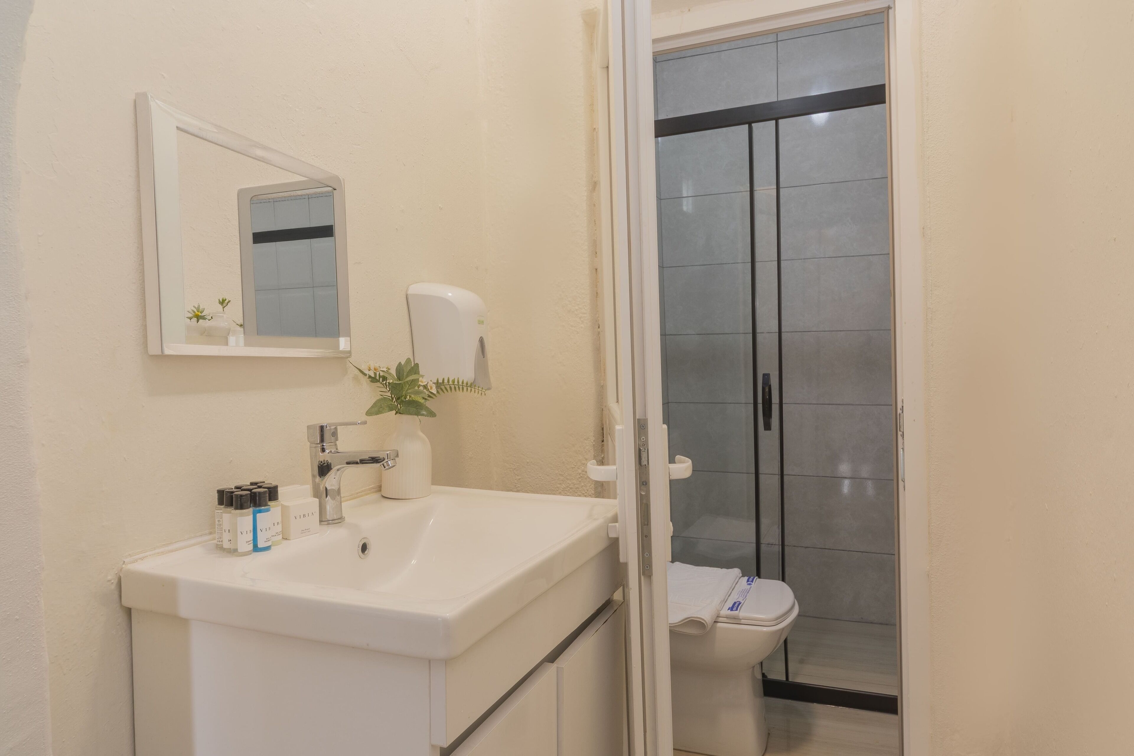 A bathroom with a white sink, mirror, and a glass shower enclosure.
