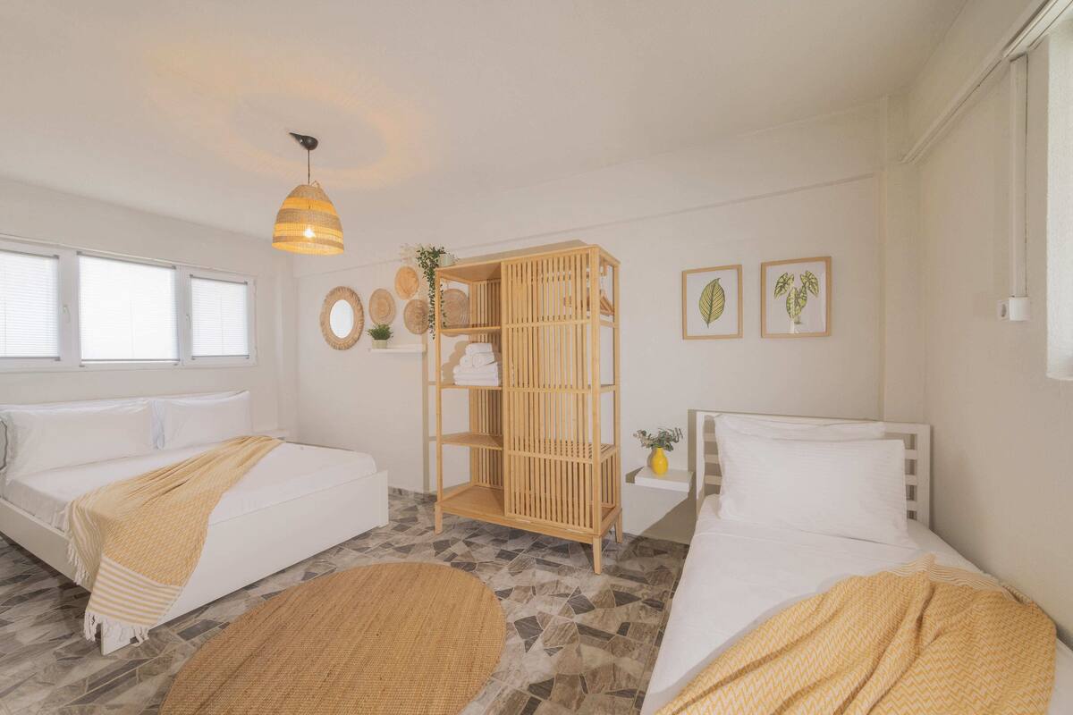 Une pièce avec deux lits, une étagère en bois, une lampe suspendue et un sol à motifs.