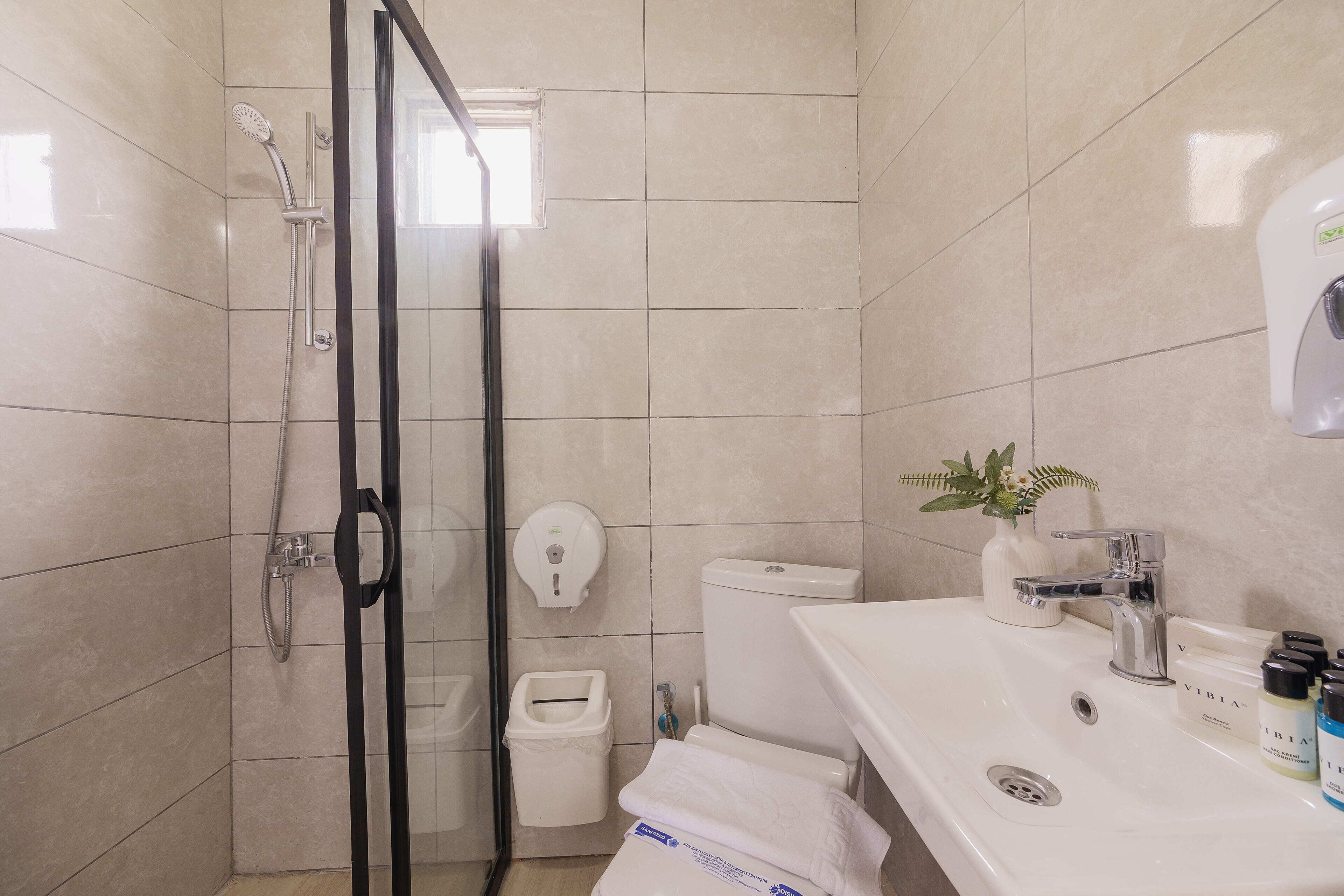 A bathroom with a shower, toilet, sink, and a hand dryer.