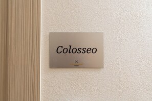 A sign with the name 'Colosseo' and the logo 'Urban Vatican Rooms' on a textured wall. - Urban Vatican Rooms 2 (Rome)