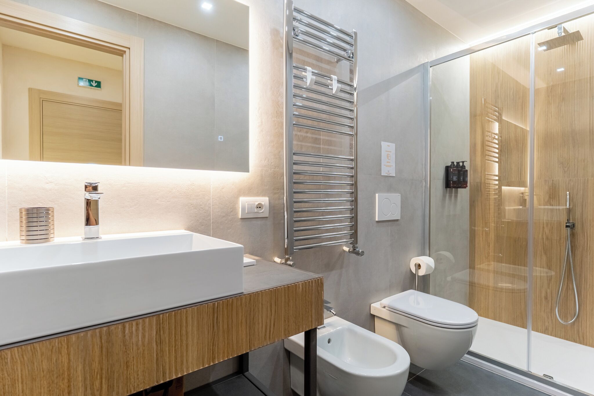 A modern bathroom with a large sink, a glass shower enclosure, and a toilet.