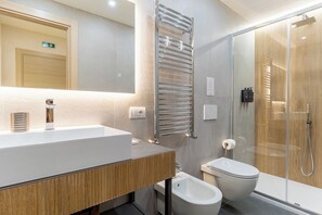 Un baño moderno con un lavamanos grande, cabina de ducha con vidrio y un inodoro.