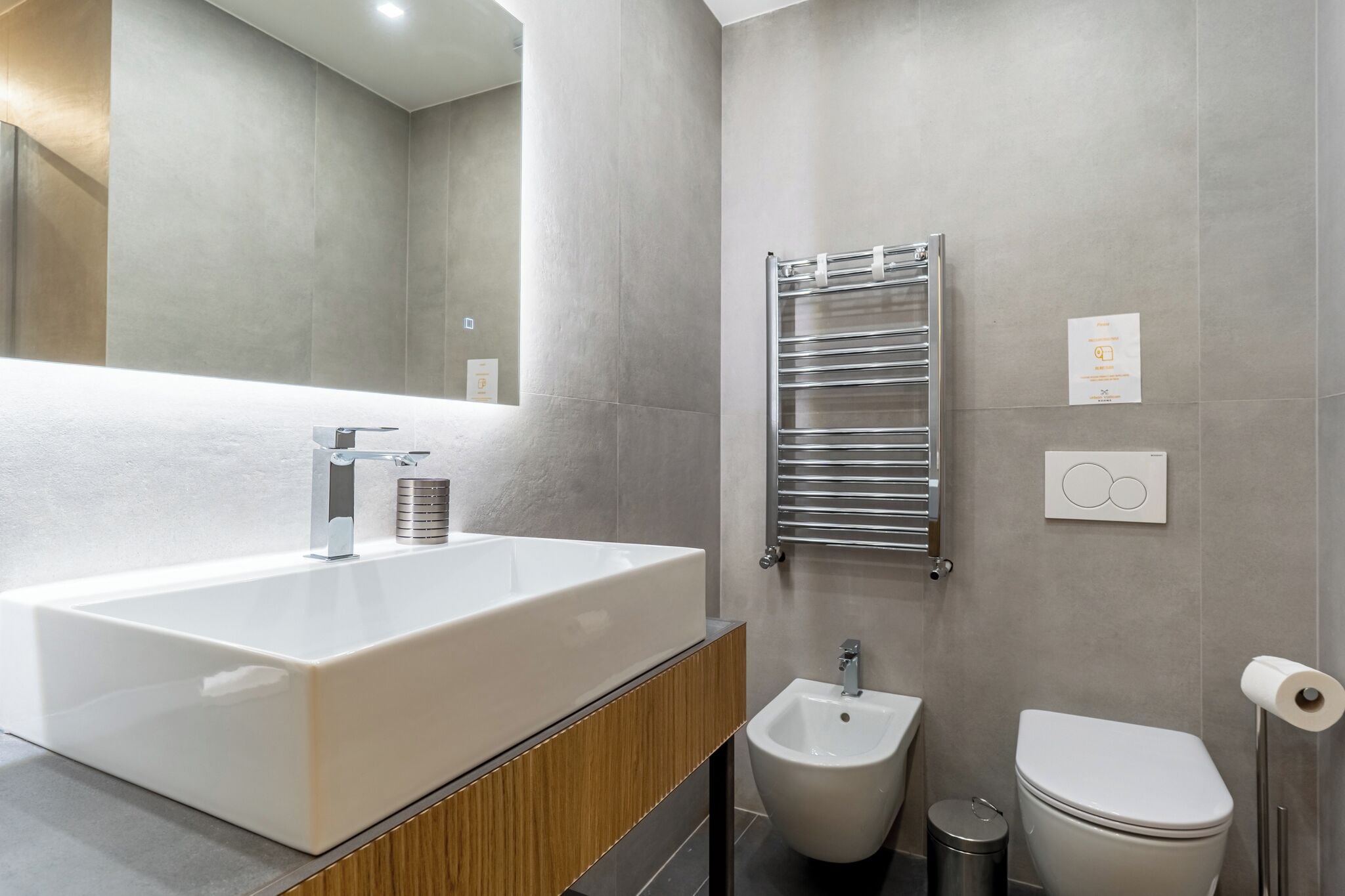 A modern bathroom with a large rectangular sink, a bidet, and a toilet.