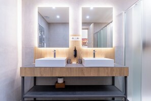 Un baño moderno con dos lavamanos, un espejo y un perchero para toallas.