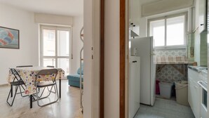 A kitchen with a refrigerator, a sink, and a window. There is a dining area with a table and chairs. - Cozy 57m2 apartment, ideal for 3 people, located on the fifth floor of a building with lift.The property is located in the Navigli area, one of the areas most loved by citizens and tourists, in a context full of services. The location is also ideal for r (Milan)