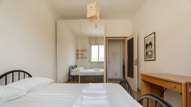 A bedroom with a bed, a desk, a chair, a mirror, and a door leading to another room. - Cozy 57m2 apartment, ideal for 3 people, located on the fifth floor of a building with lift.The property is located in the Navigli area, one of the areas most loved by citizens and tourists, in a context full of services. The location is also ideal for r (Milan)