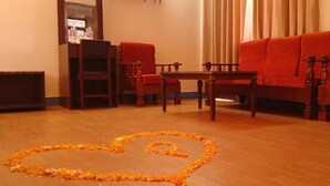 Una sala de estar con un arreglo floral en forma de corazón sobre el suelo, una mesa de centro de madera y sofás tapizados en rojo.