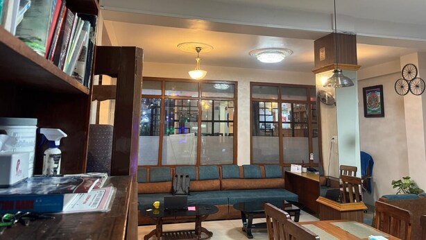 Una habitación con sofá, una mesa, una estantería y una ventana con persianas.