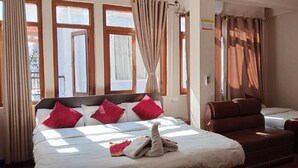 Una habitación de hotel con cama, sofá, una mesita y una ventana con cortinas.