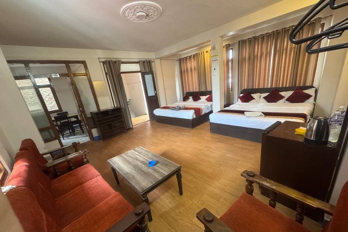 A hotel room with two beds, a sofa, a small table, and a TV.
