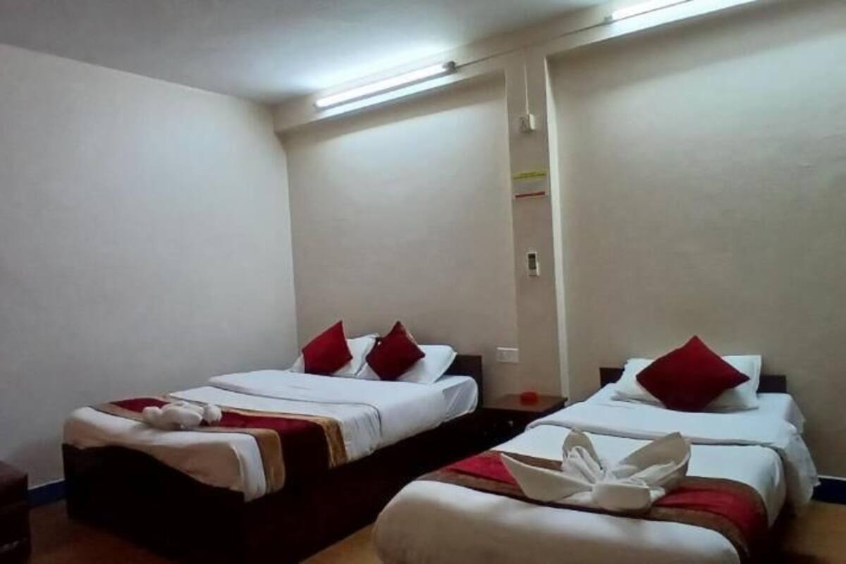A hotel room with two beds, a chair, and a small table.