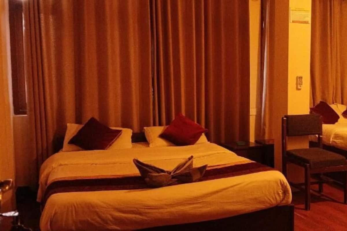A hotel room with two beds, a desk, and a chair.