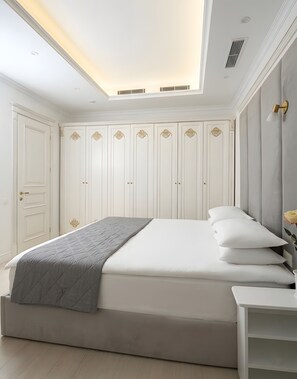 A bedroom with a large bed, a bedside table, a wardrobe, and a ceiling light fixture. - Seven Beauties Hotel & SPA (Baku)