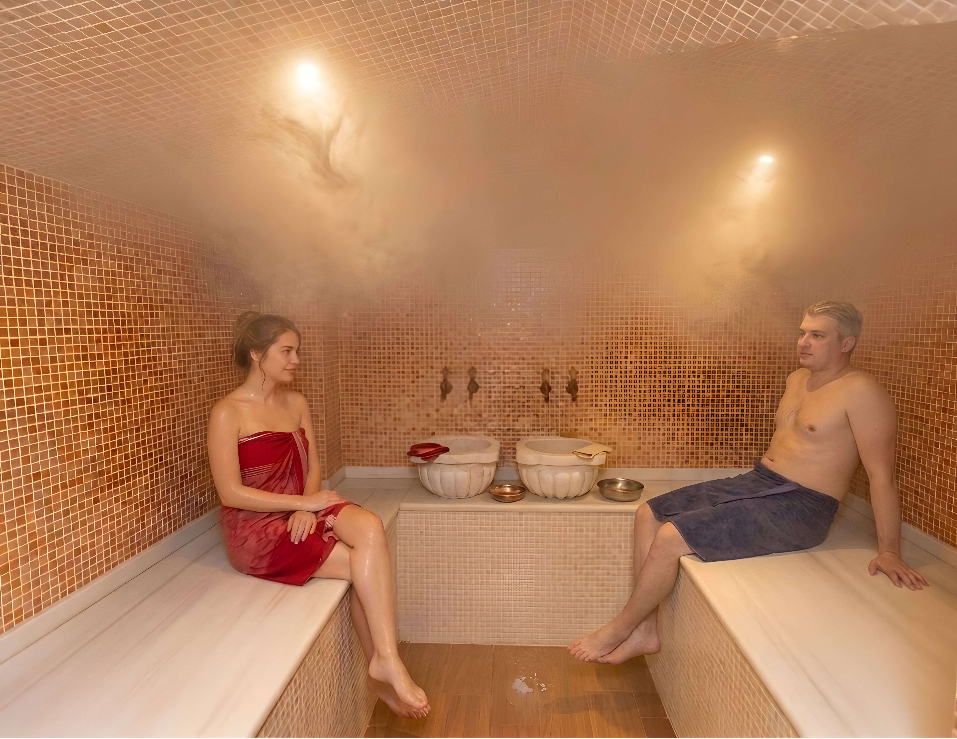 A sauna with tiled walls and benches, a bench with a towel, and a bench with a towel.