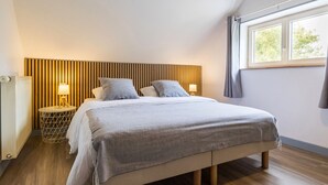 Ein Schlafzimmer mit Bett, Nachttischlampen, Heizkörper und Fenster.