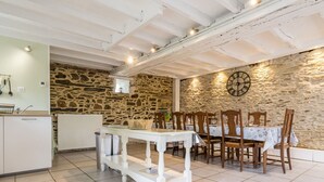 Ein Essbereich mit Steinwand, einer Uhr und einem weißen Tisch mit Stühlen.