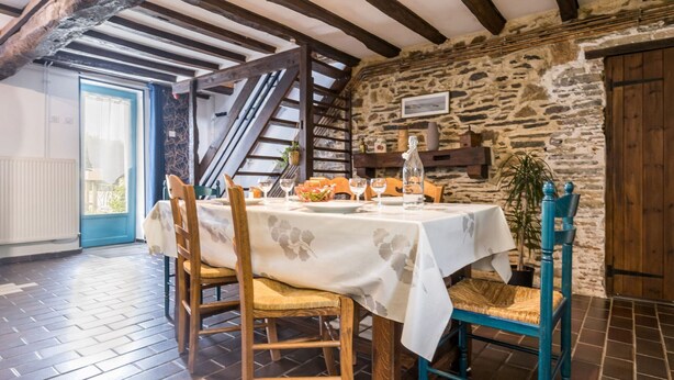 Un comedor con pared de piedra, vigas de madera y una mesa dispuesta para dos.